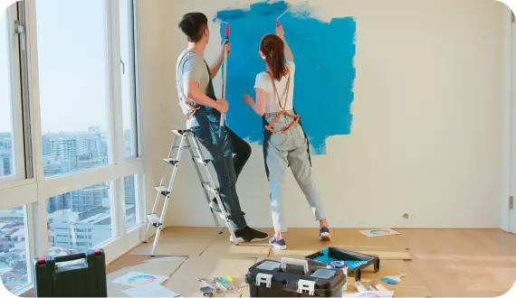 dziewczyna i chłopak malują ścianę na niebiesko